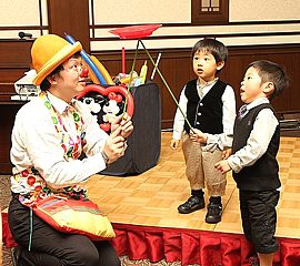 男の子に皿回し体験をさせてあげる大道芸人