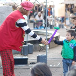 小さな男の子にバルーンを作って渡すクラウン（ピエロ）