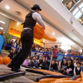 ハロウィンイベントでかぼちゃのバルーンアートを作る男性パフォーマー