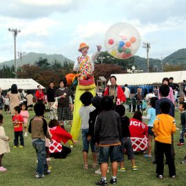 お祭りでスパークバルーンをするスティルトパフォーマー