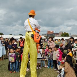 イベントで子ども達に囲まれるハロウィンの衣装のスティルトパフォーマー