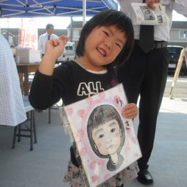 女性似顔絵師が描いた似顔絵を嬉しそうに持っている女の子