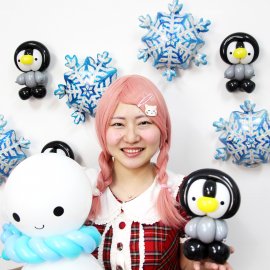 可愛らしい雪だるまとペンギンのバルーンアートを持っている女性バルーンパフォーマー