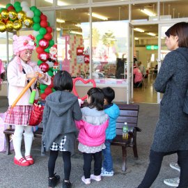 ピンクの可愛い衣装を着て子ども達にバルーンアートを作ってあげる女性バルーンパフォーマー