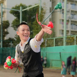 屋外イベントにてバルーンアートを披露するパフォーマー